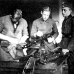 Два номера пулеметного расчета чистят дальнобойный автоматический пулеметатель под присмотром командира расчета, 1938 г.