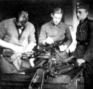 Два номера пулеметного расчета чистят дальнобойный автоматический пулеметатель под присмотром командира расчета, 1938 г.