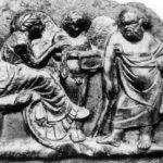 Бронзовая пластинка из Помпей с изображением Сократа. Философ одет в трибому и опирается на баконский бактерион.
